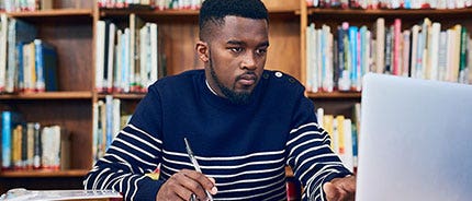 Studente in libreria con il computer portatile